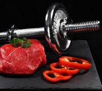 un haltère à côté d'une viande et des tranches de tomate